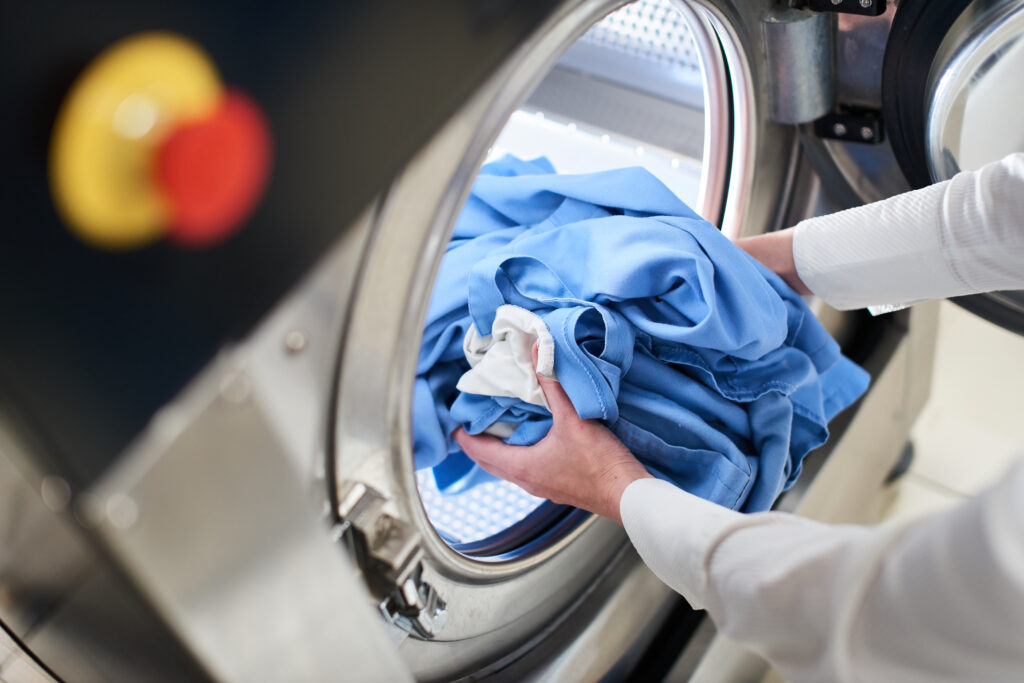 hands loading laundry into washing machine dry cleaning hands loading laundry into washing machine dry cleaning