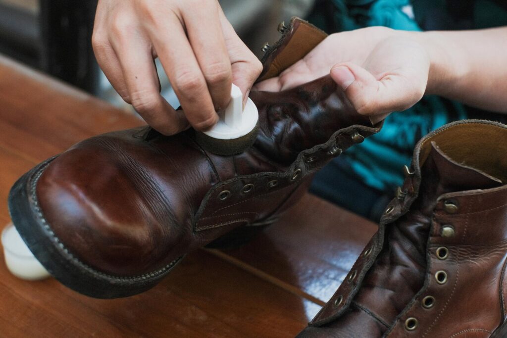 close up hands polishing leather boots with mink oil with sponge wooden table 1165376 1761 close up hands polishing leather boots with mink oil with sponge wooden table 1165376 1761